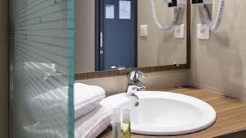 Un baño con un lavabo blanco, un espejo y un secador de pelo montado en la pared.