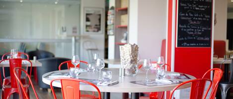 A restaurant with red chairs and tables, a blackboard menu, and a modern interior design.