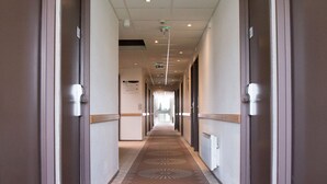 Een hotelgang met een kamerbreed tapijt, deuren aan beide kanten en een plafond met inbouwverlichting.