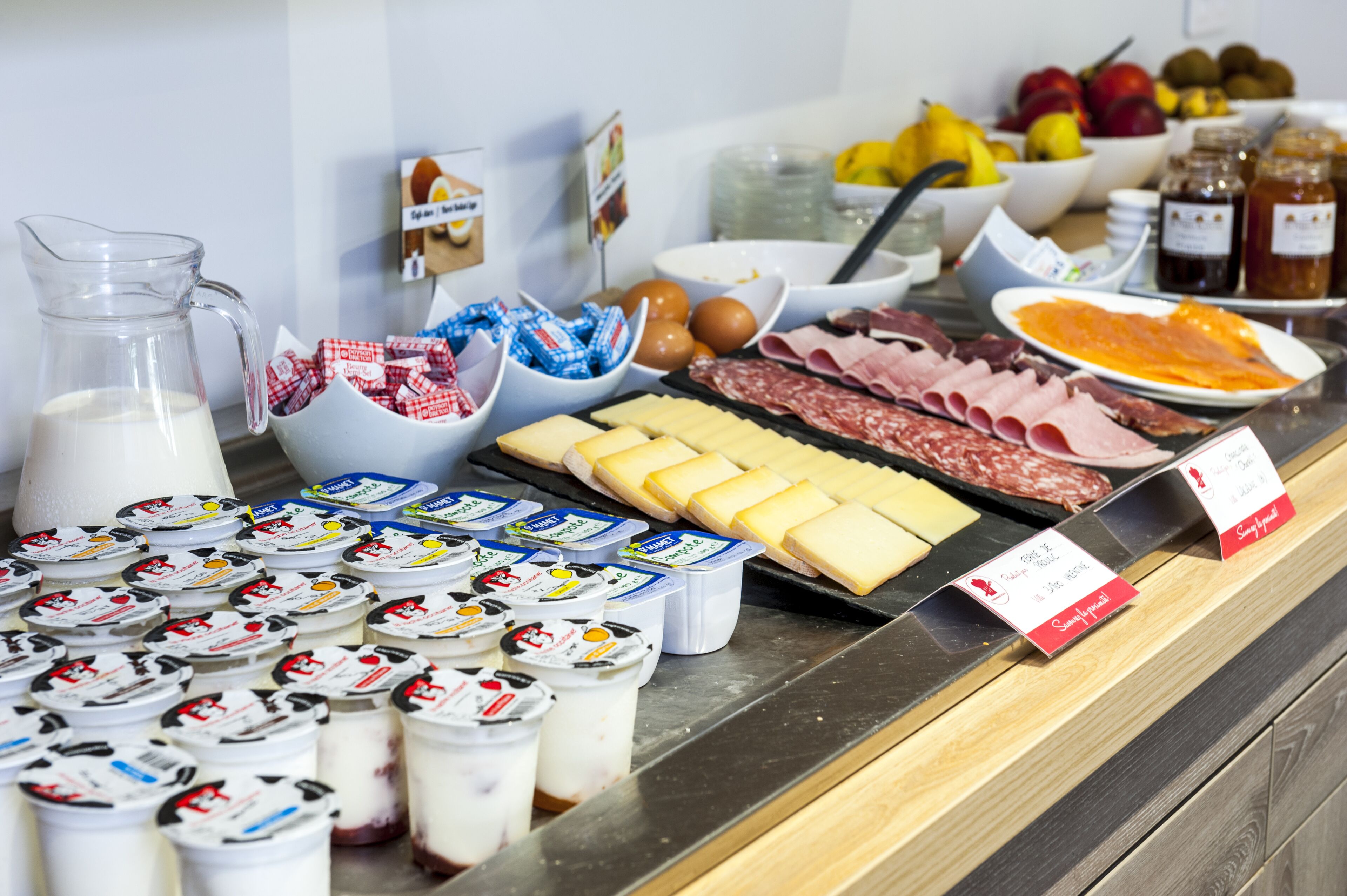 A variety of food items including cheeses, meats, and dairy products displayed on a counter.