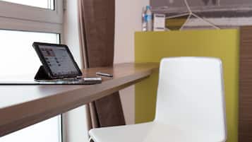 Un espace de travail moderne avec une tablette posée sur un bureau, une chaise blanche et un séparateur jaune.