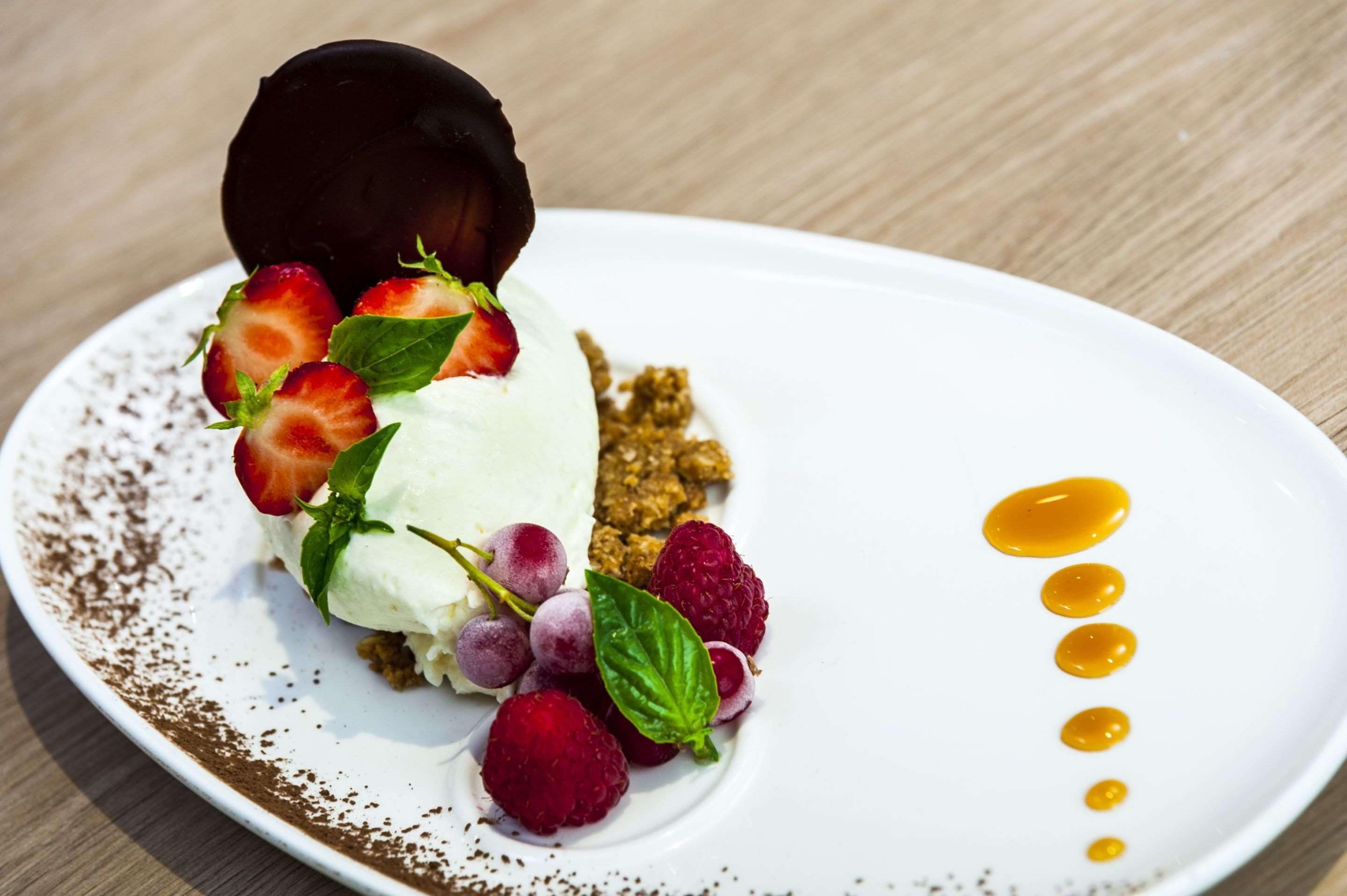 Een dessertborden met een bolletje ijs, aardbeien, frambozen en een stukje chocolade.