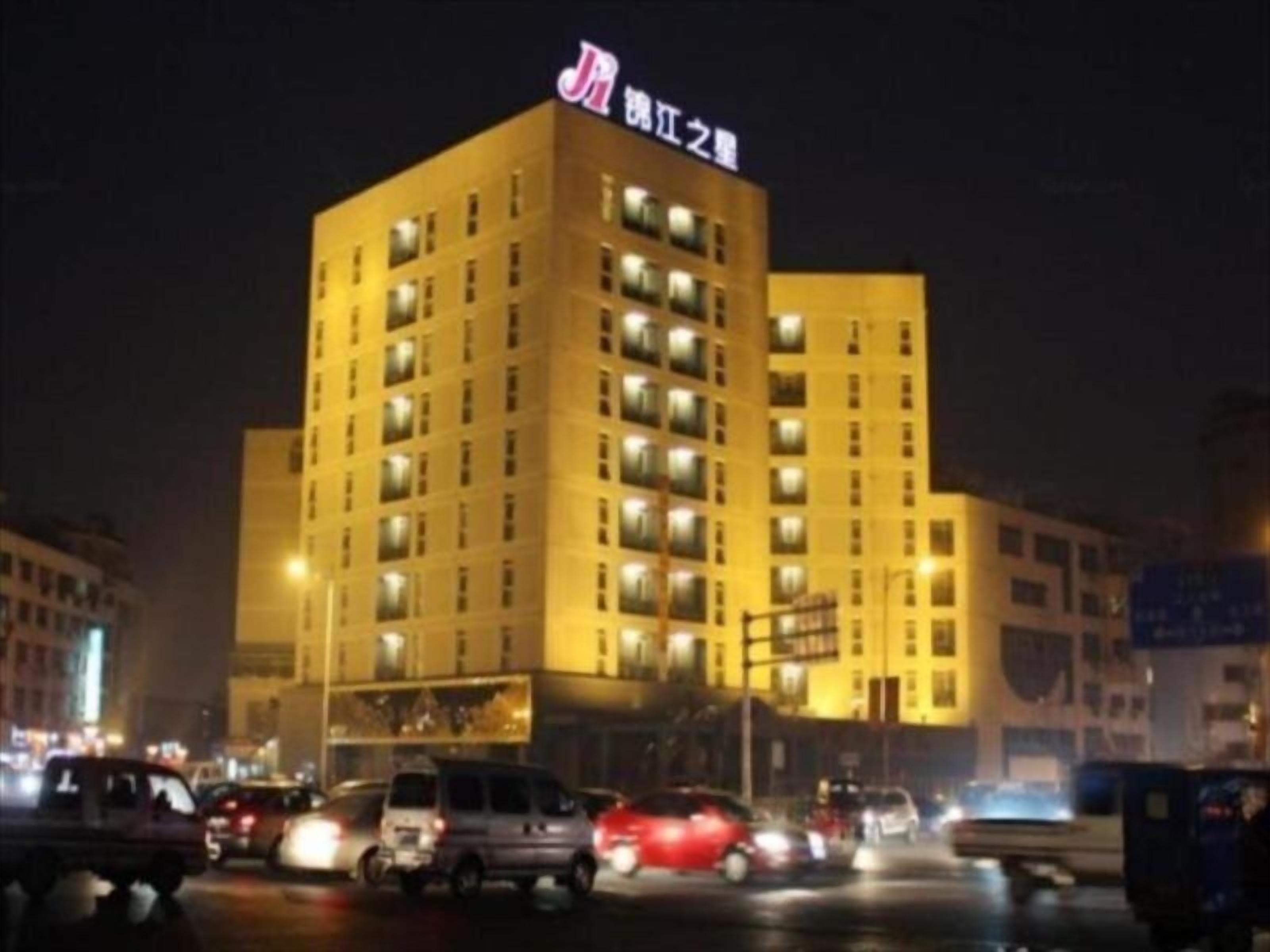 Un hotel de varios pisos con ventanas iluminadas y un letrero llamativo en la parte superior.