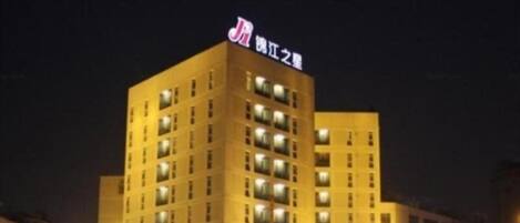 Un hotel de varios pisos con ventanas iluminadas y un letrero llamativo en la parte superior.