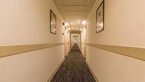 Un pasillo de hotel con pisos alfombrados, paredes color beige y cuadros enmarcados.