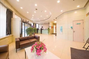 Un hall d’hôtel comprenant un comptoir d’accueil, un espace détente avec un canapé et une plante en pot.
