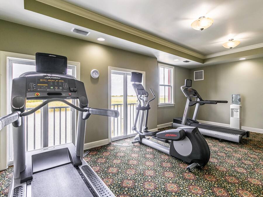 A gym with treadmills, elliptical machines, and a stationary bike.