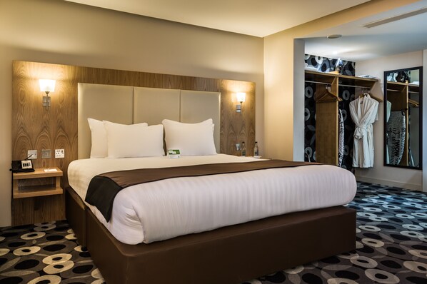 Een hotelkamer met een groot bed, nachtkastjes, een kledingkast en een spiegel.