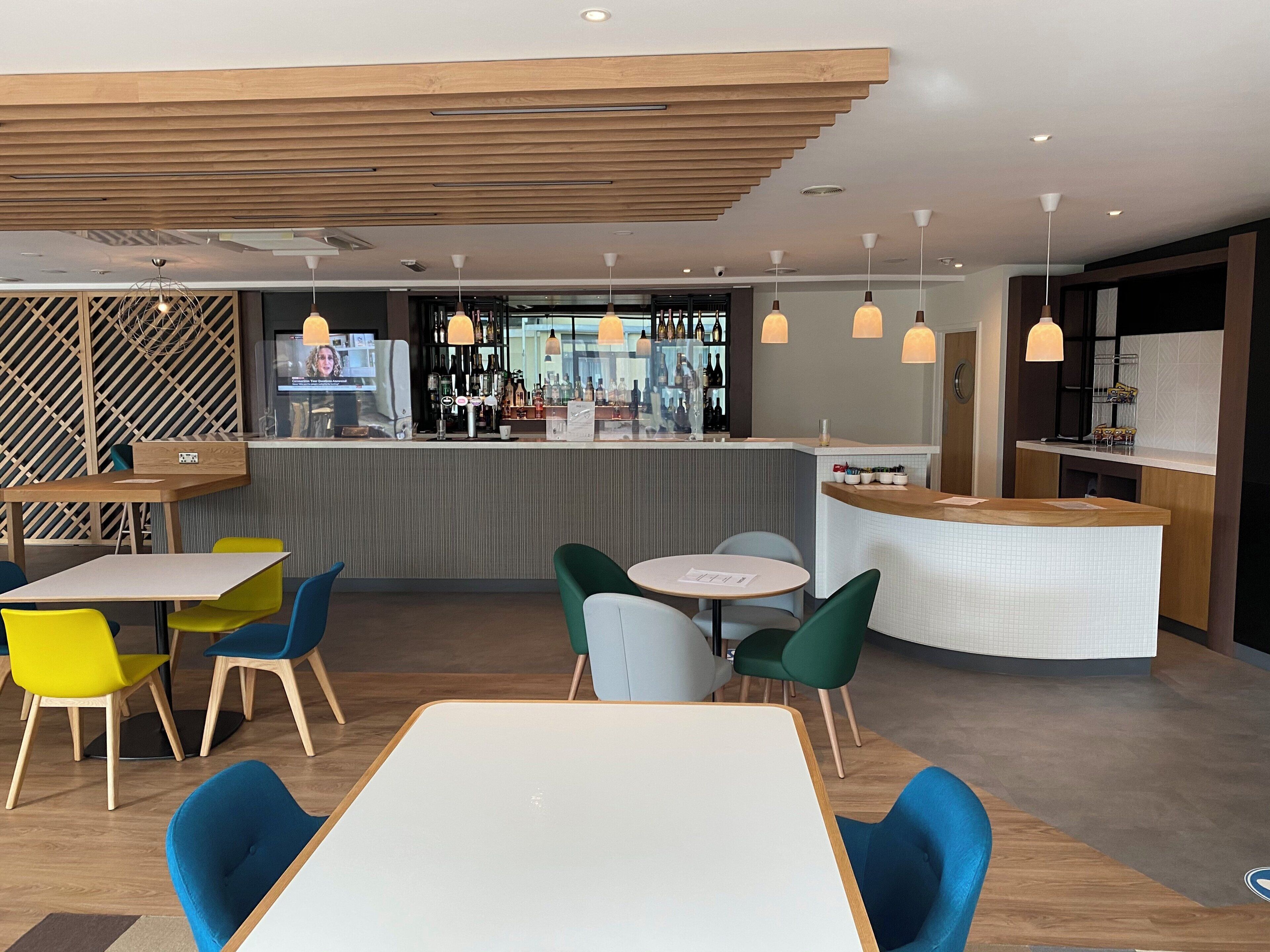 Zona de bar moderna con mostrador, taburetes y una variedad de botellas.