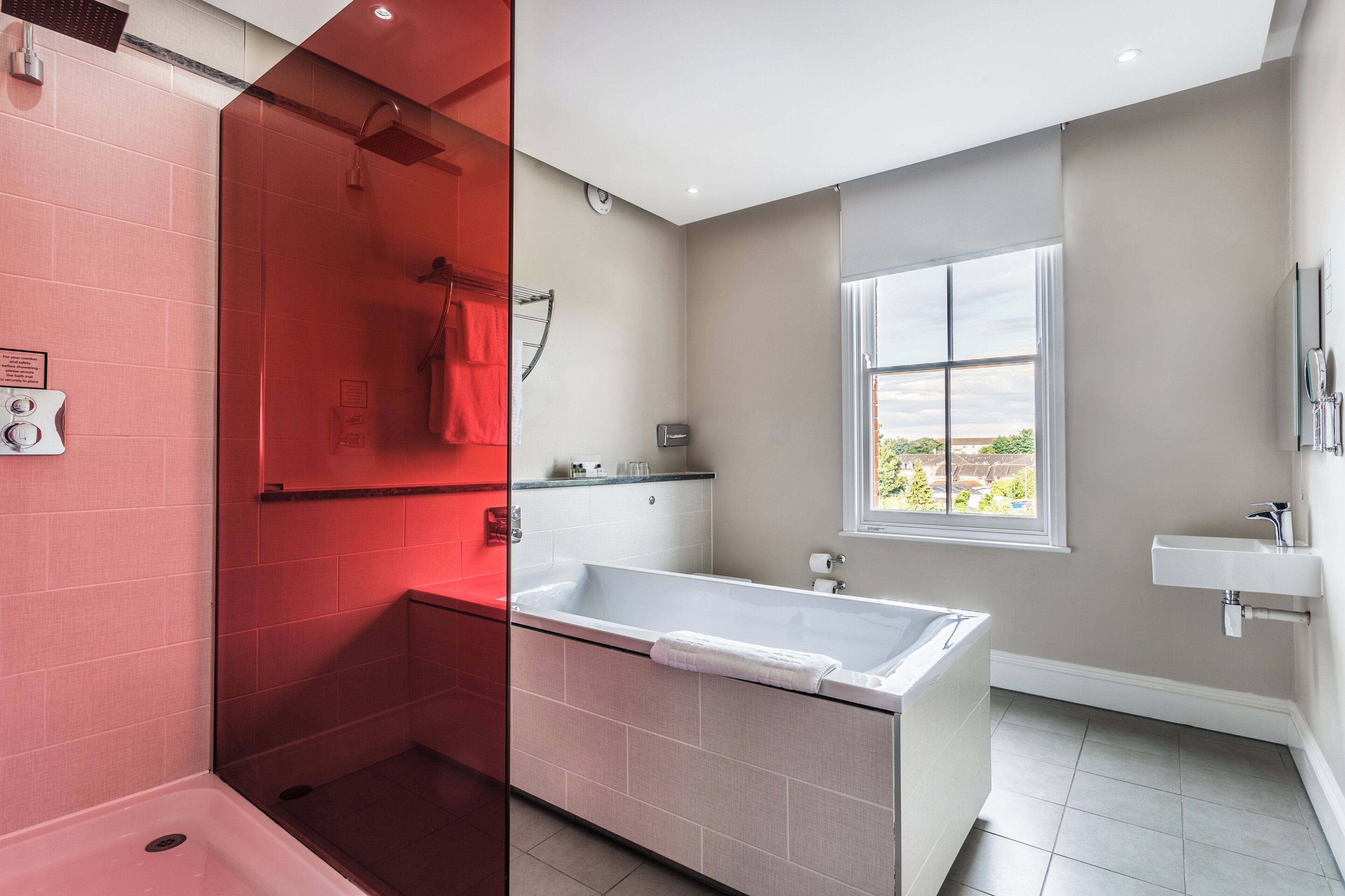 Un baño moderno con bañera, ducha y ventana que ofrece vistas.