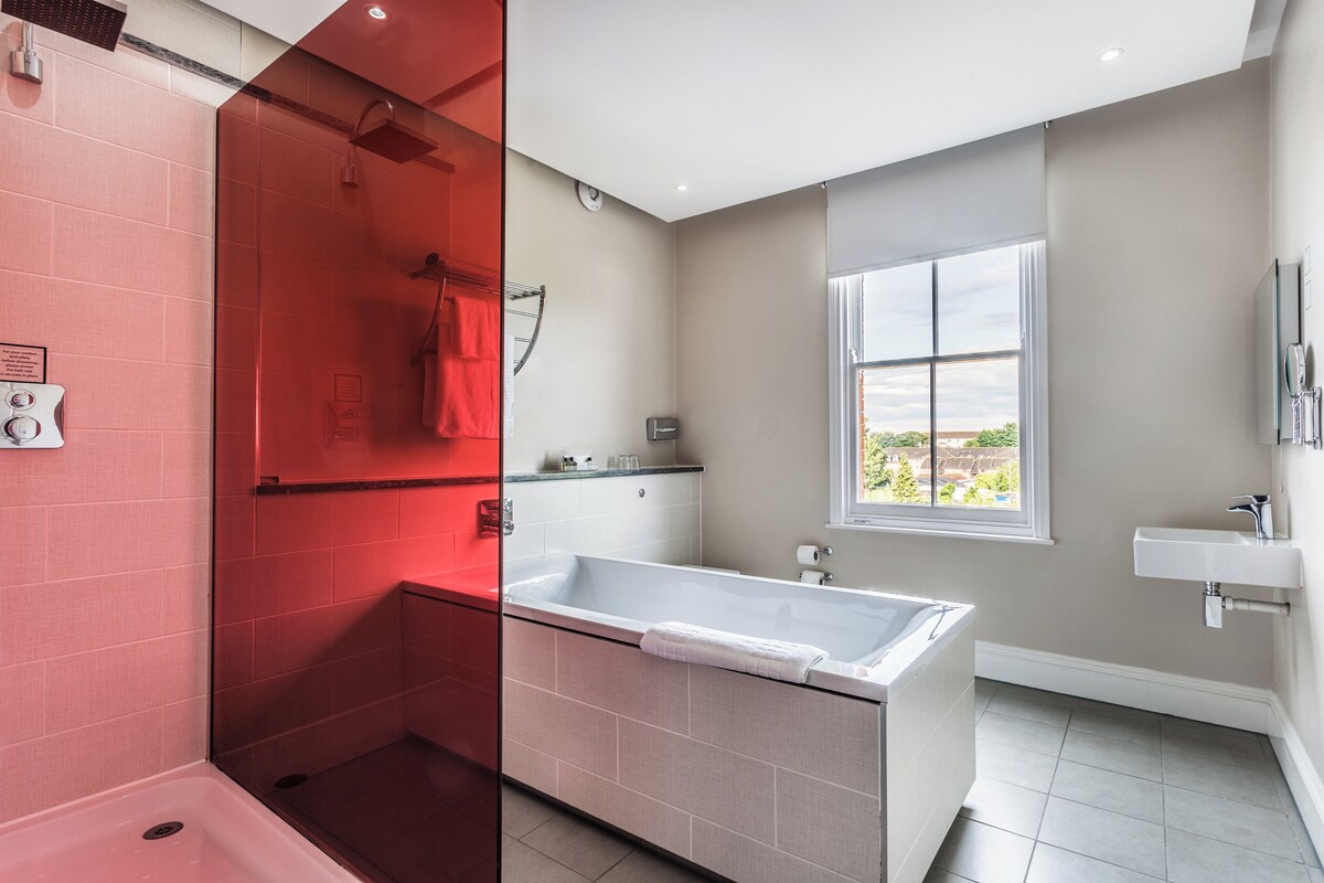 Een moderne badkamer met een bad, een douche en een raam met uitzicht.