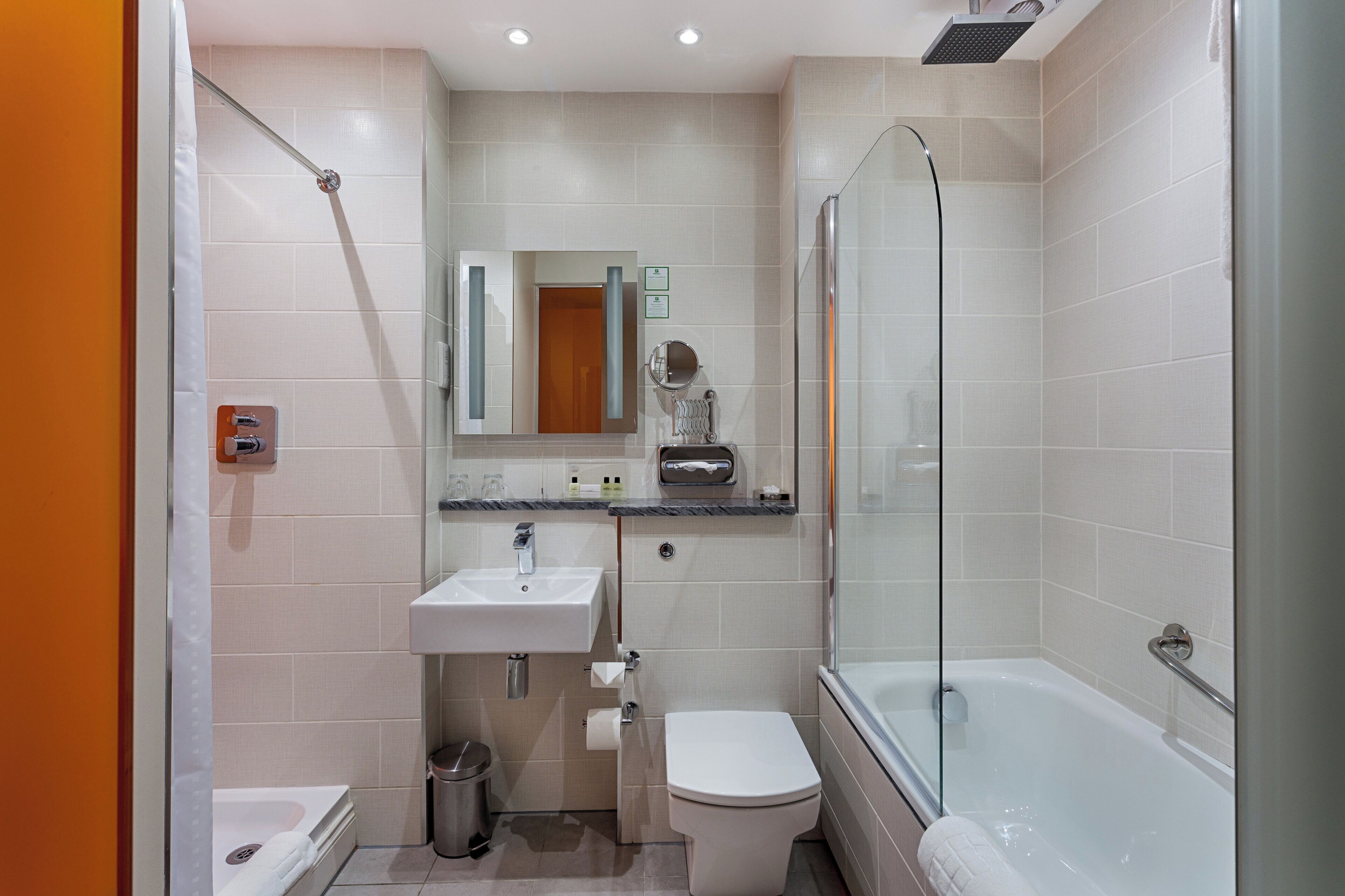 A modern bathroom with a glass-enclosed shower, a white sink, and a toilet.