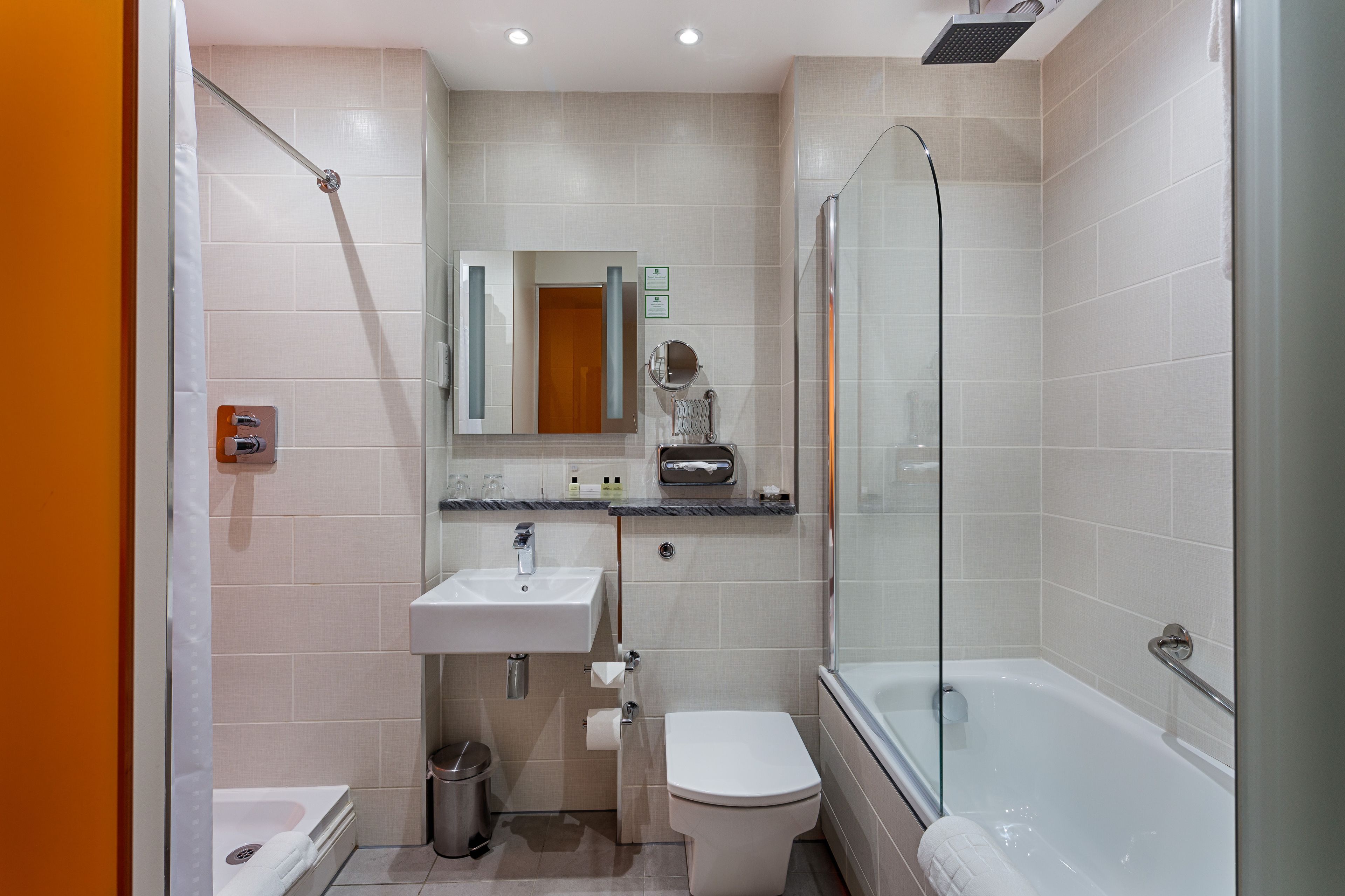 A modern bathroom with a glass-enclosed shower, a white sink, and a bathtub.