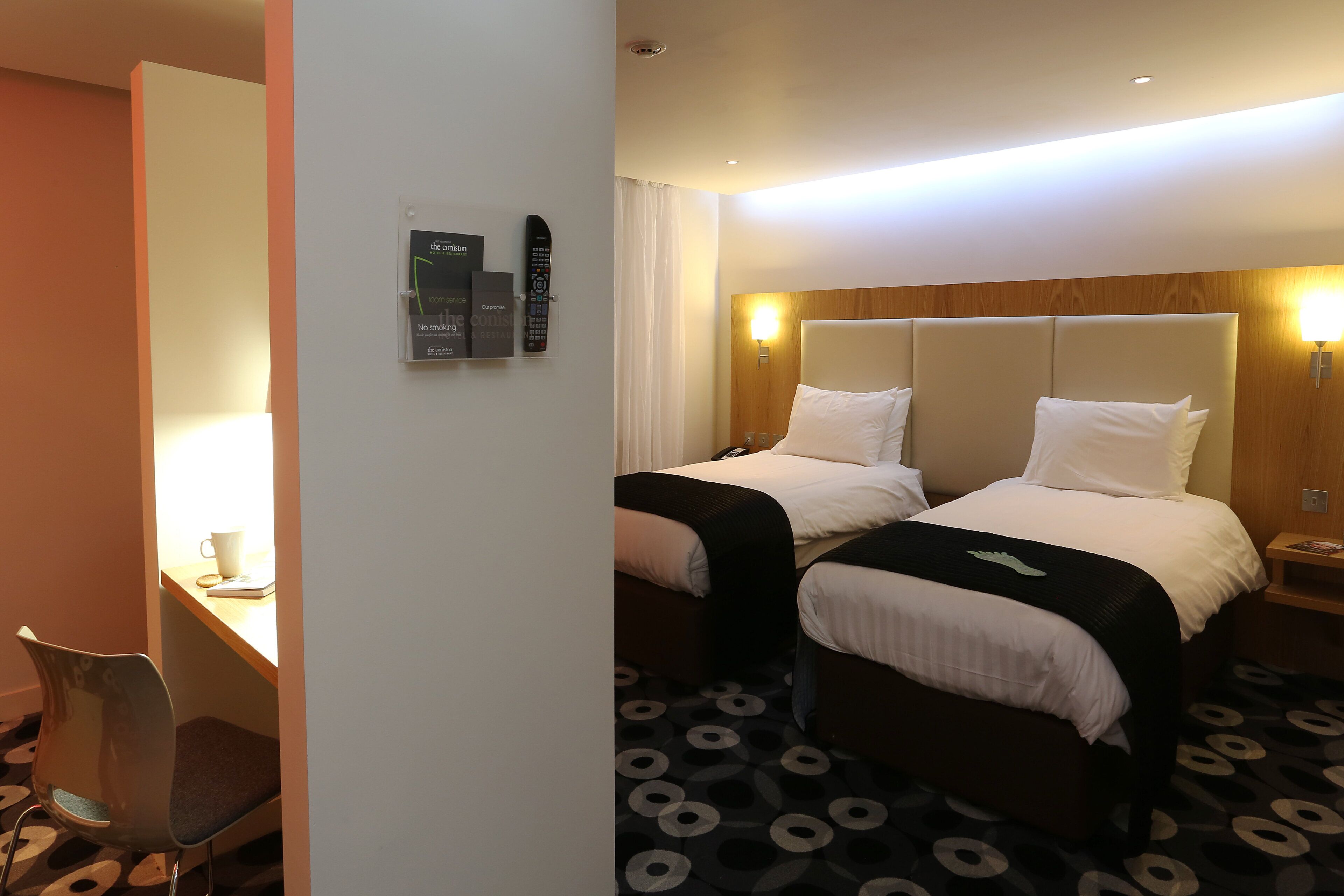 Habitación de hotel con dos camas, un escritorio y una silla.