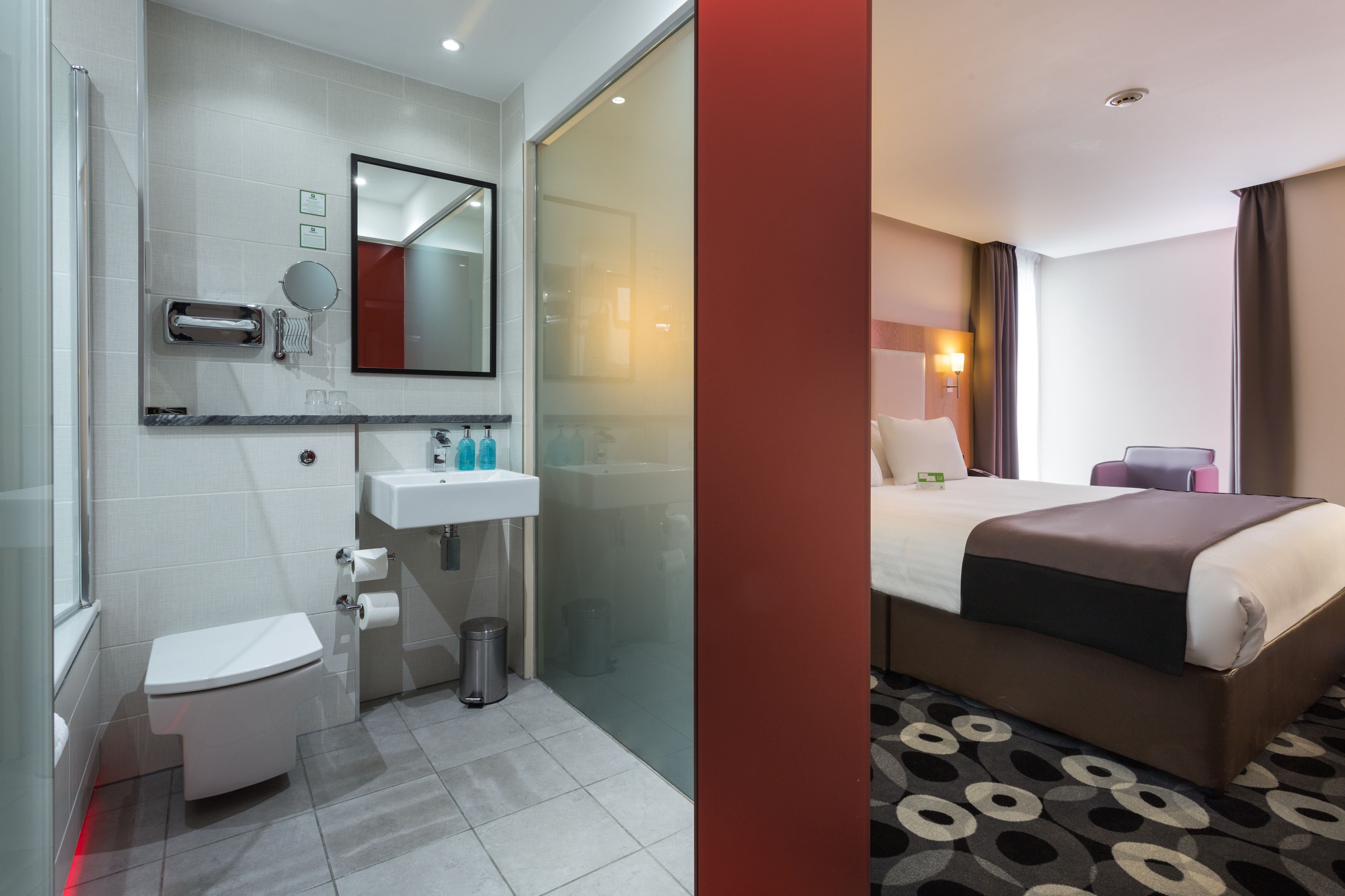 Una habitación de hotel con baño, cama y ventana.