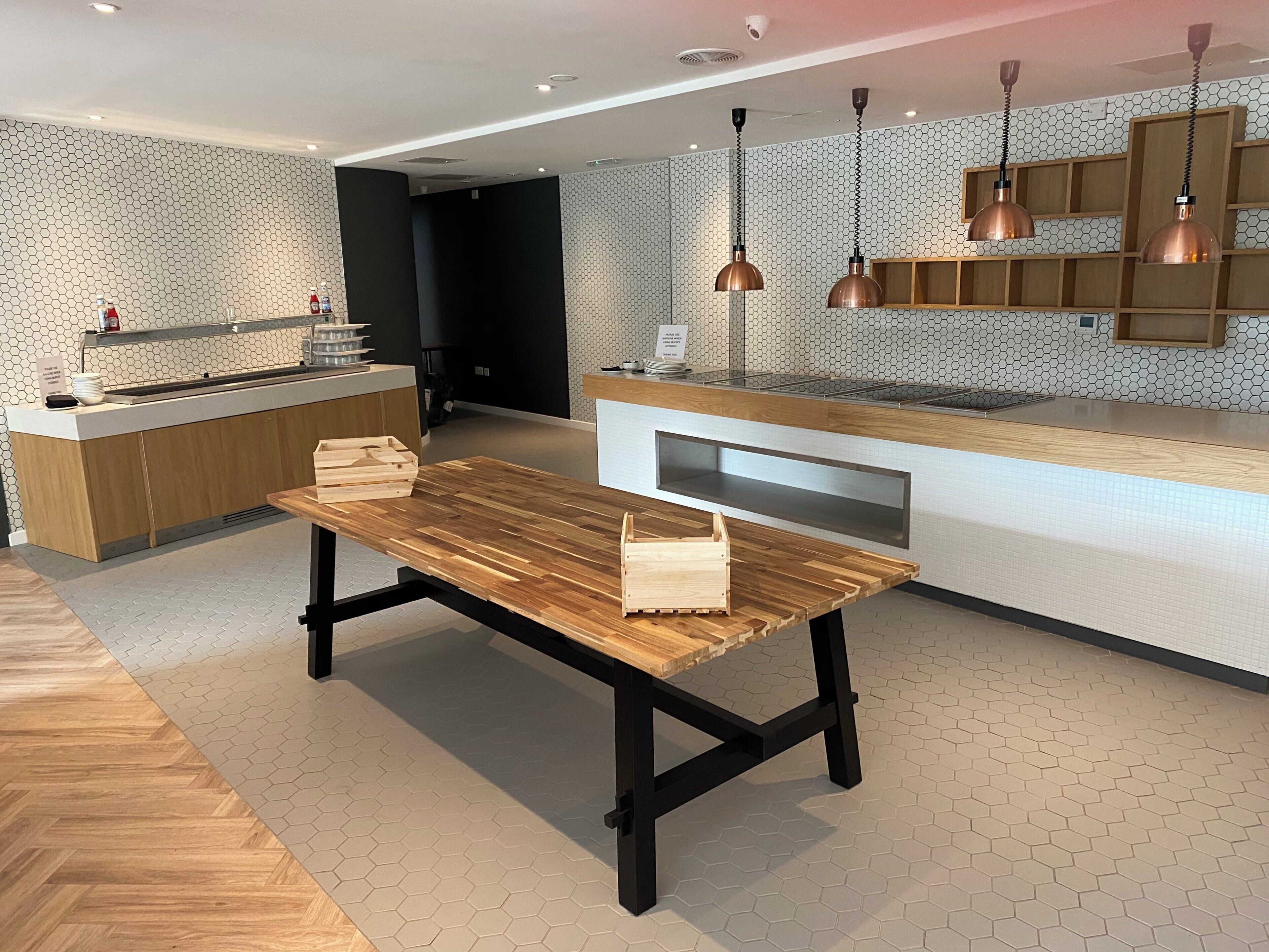 A modern kitchen with a wooden table, pendant lights, and a hexagonal patterned backsplash.