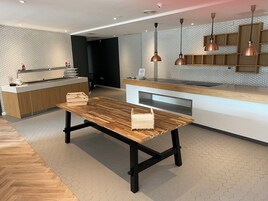 A modern kitchen with a wooden table, pendant lights, and a hexagonal patterned backsplash.
