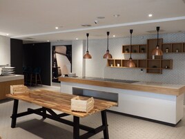 A modern kitchen with a wooden table, pendant lights, and a hexagonal patterned backsplash.