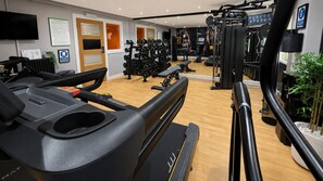 A gym with cardio equipment, weight machines, and a mirror.
