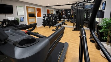 A gym with cardio equipment, weight machines, and a mirror.