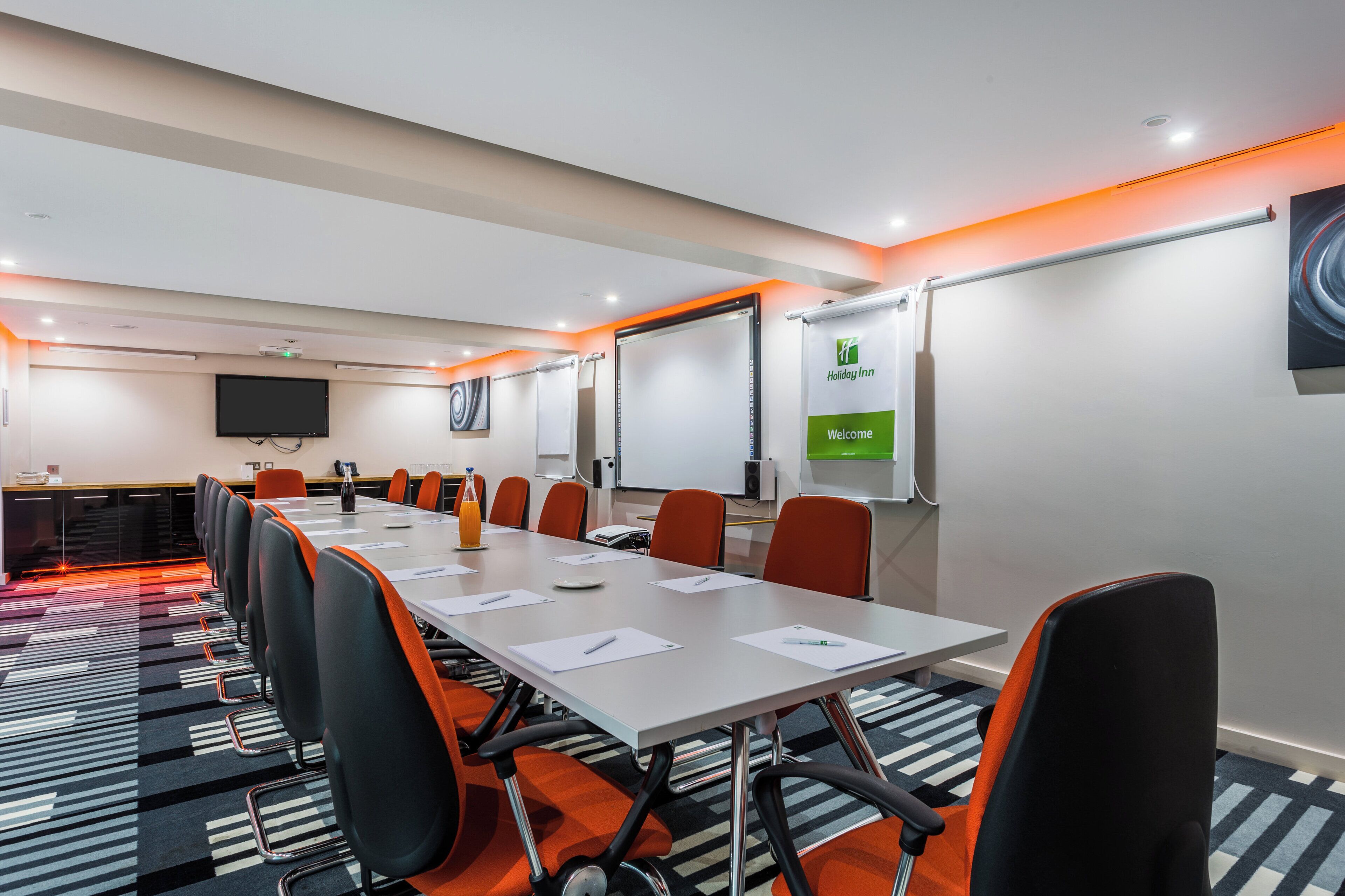 A conference room with a long table, chairs, a projector, and a whiteboard.