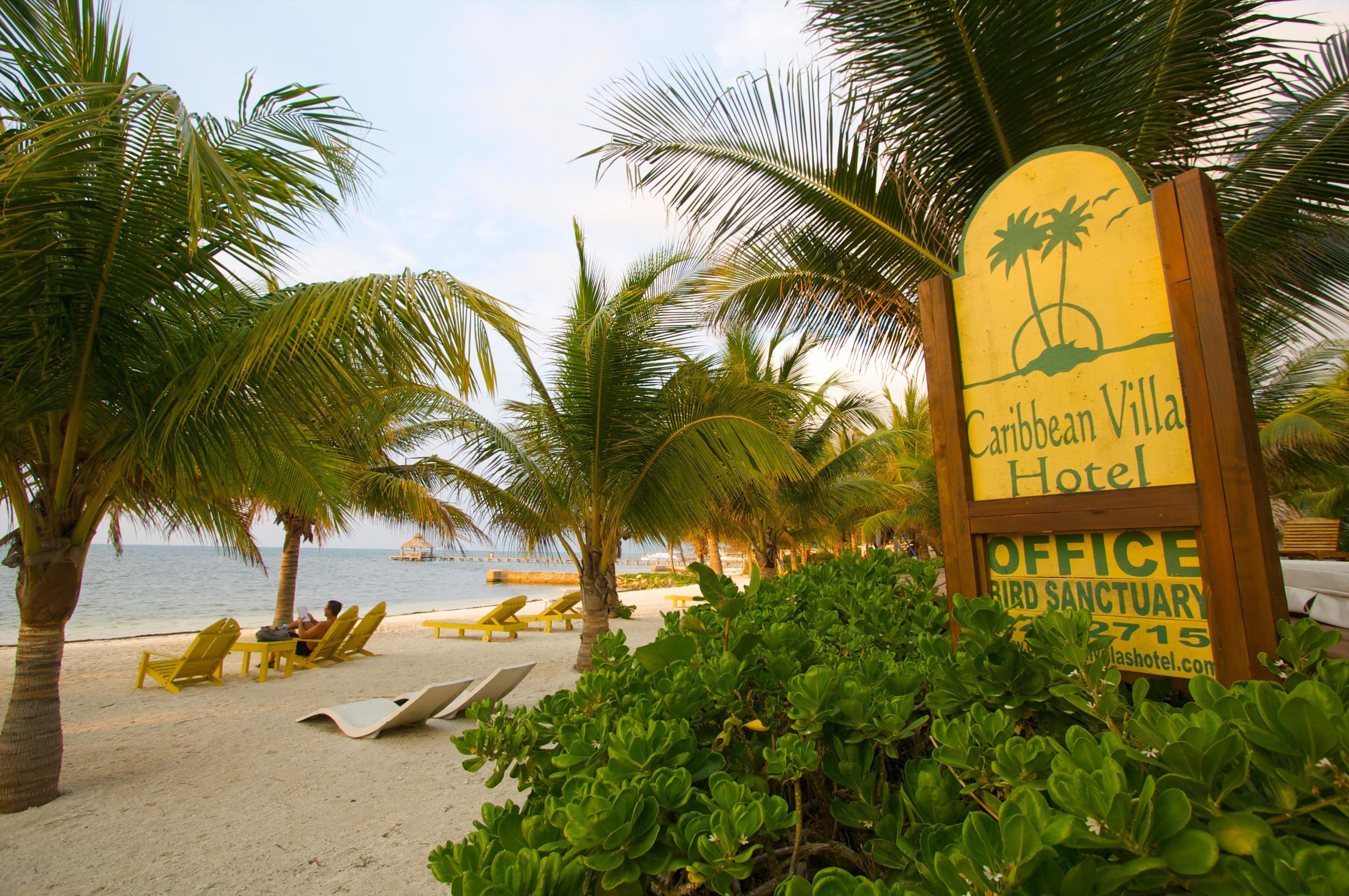 Een strand met een bord voor Caribbean Villa Hotel, inclusief een kantoor en een vogelreservaat.