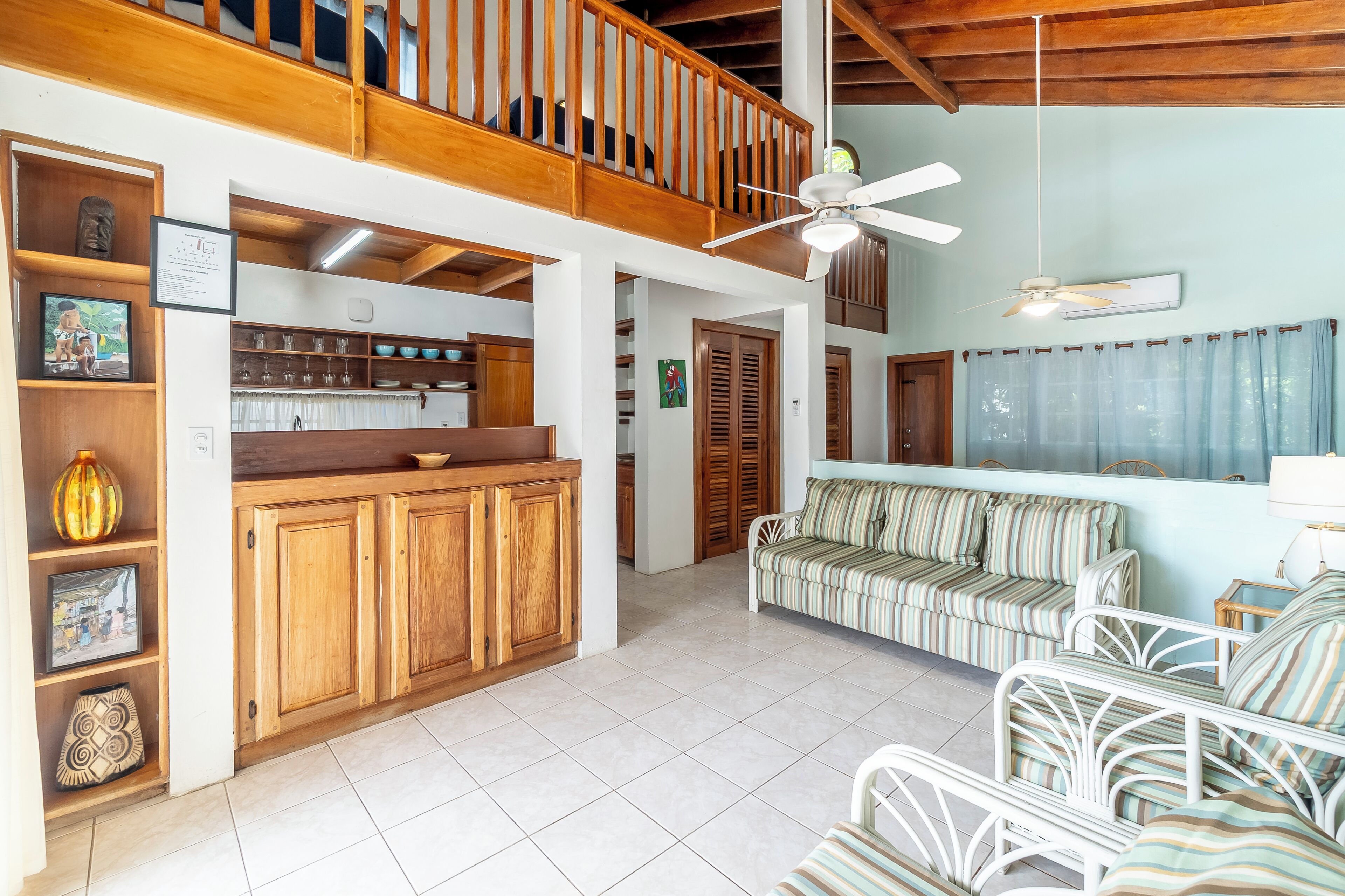 A spacious living area with a wooden balcony, a sofa set, and a kitchen area with wooden cabinets.