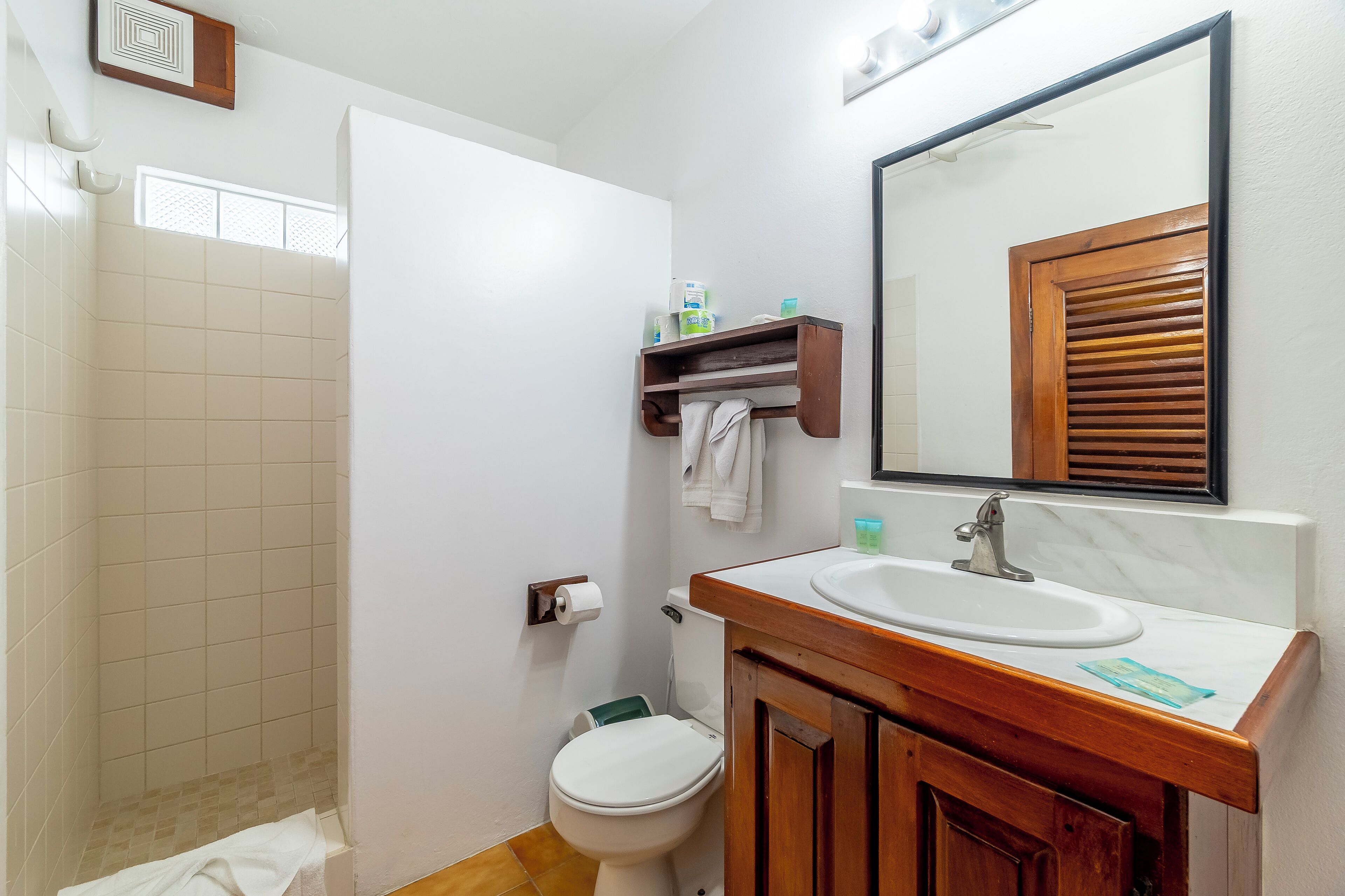 A bathroom with a shower, toilet, sink, and mirror.