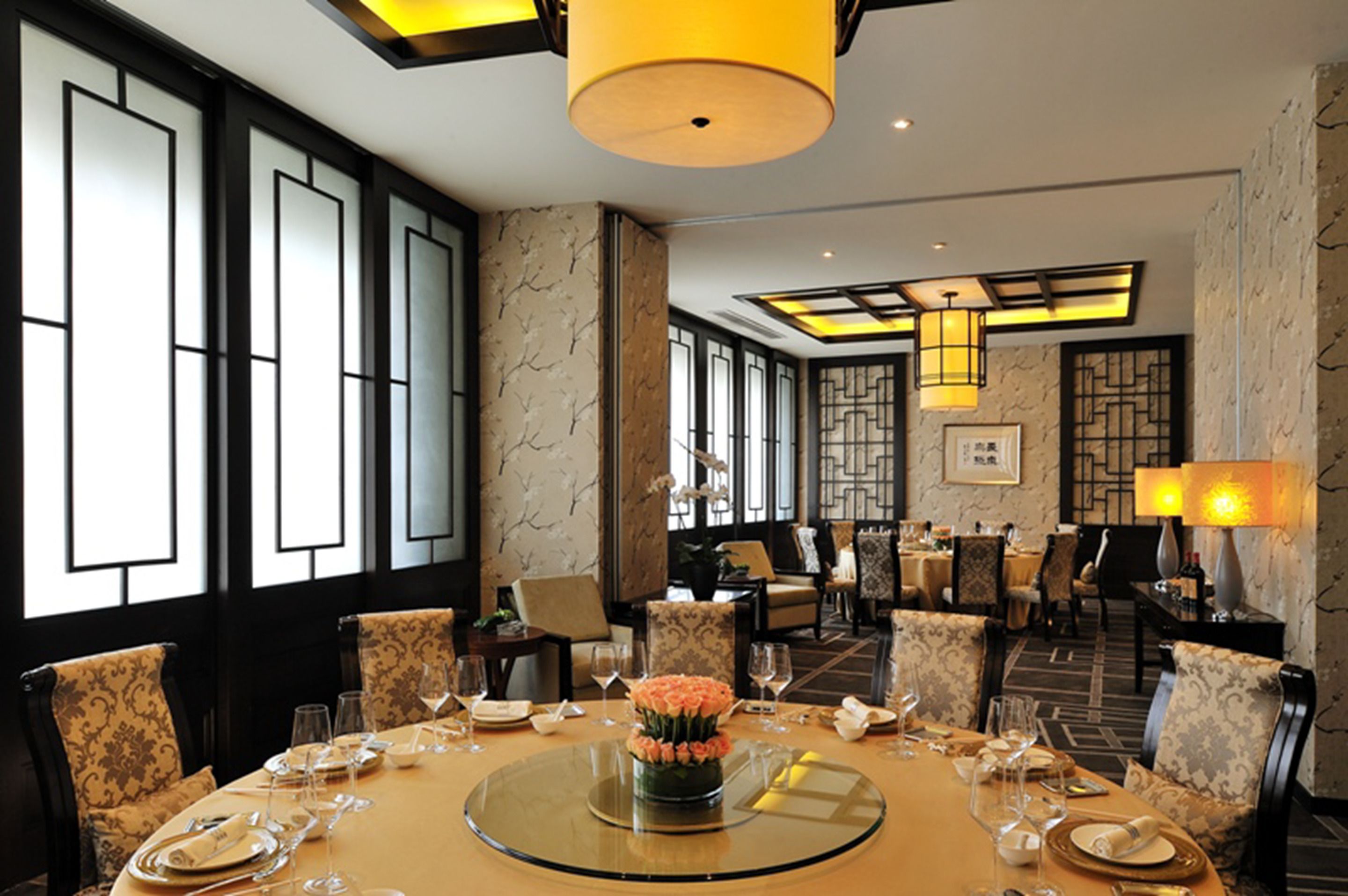 A dining area with a round table set for a meal, surrounded by chairs.