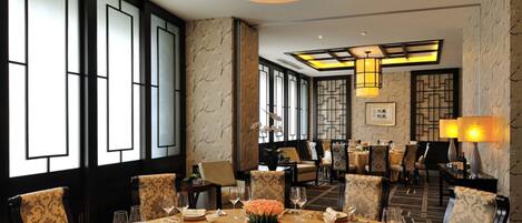 A dining area with a round table set for a meal, surrounded by chairs.