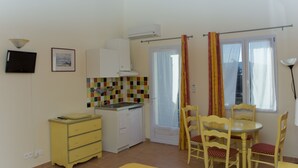 A compact kitchen with a tiled backsplash, a small dining table with chairs, and a window with curtains.