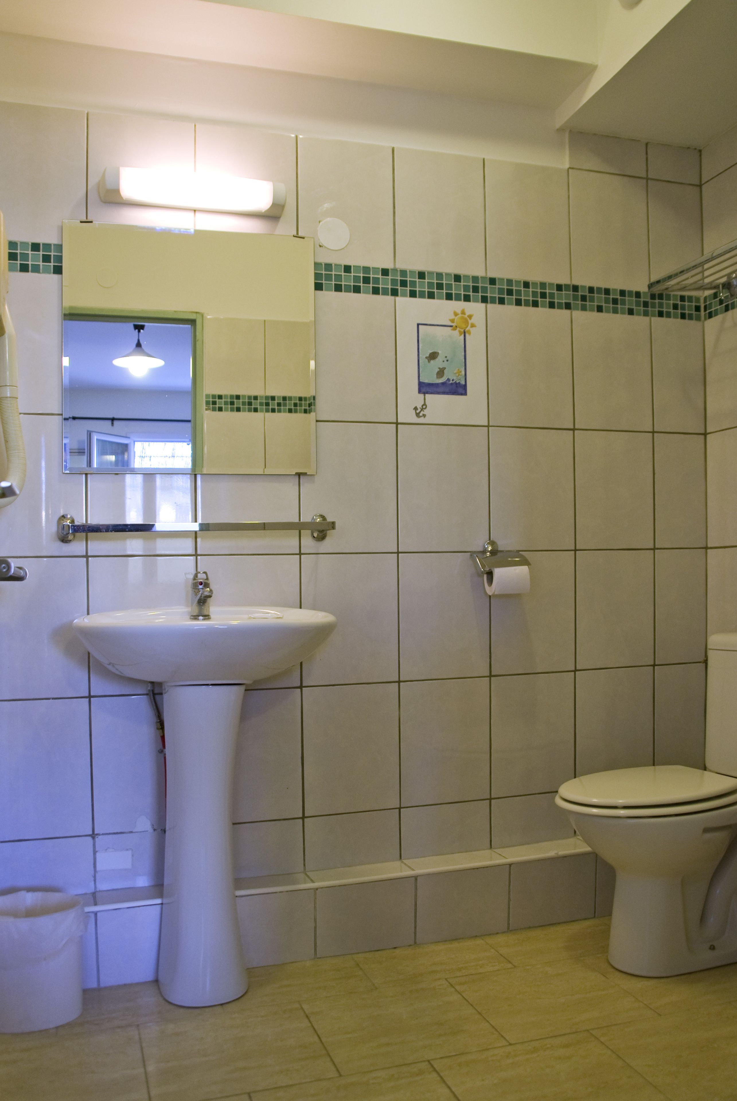 A bathroom with a sink, toilet, and a mirror.