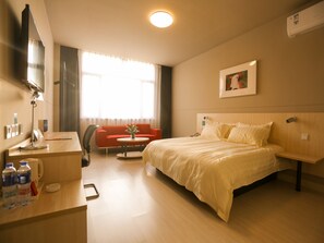 Hotelkamer met een bed, bureau, stoel, televisie en raam met gordijnen.
