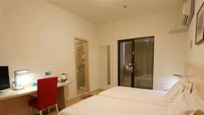 Une chambre d’hôtel avec un lit, un bureau et une chaise, une télévision et une porte de salle de bain.
