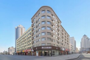 A multi-story hotel with a curved facade, multiple balconies, and a ground-level commercial area with signage.