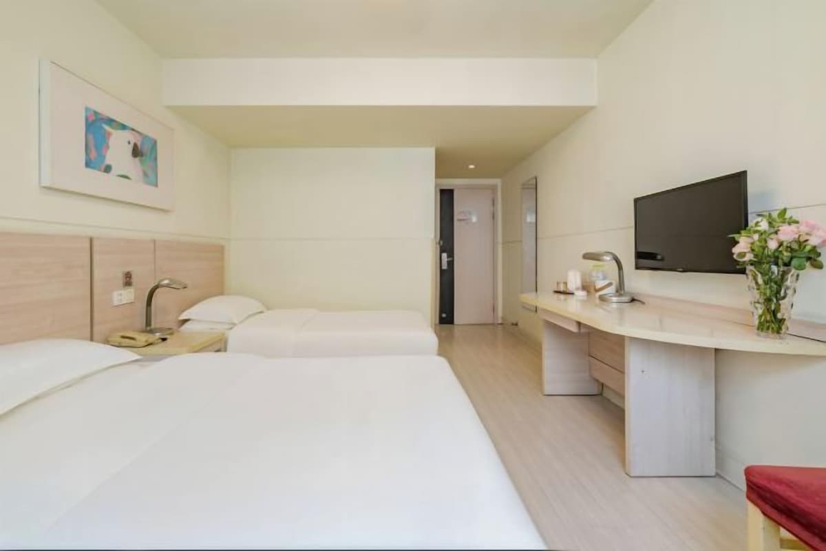 Une chambre d’hôtel moderne équipée de deux lits, d’un bureau, d’une télévision et d’une petite salle de bain.