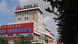 A hotel with a prominent red and white sign, a multi-story building, and a parking lot in front.