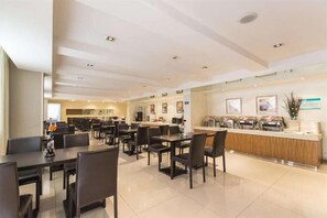 Eine moderne Hotelhalle mit Rezeption, einer Sitzecke und einer Küche im Hintergrund.