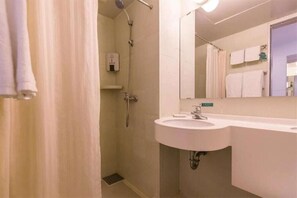 Ein Badezimmer mit Dusche, Waschbecken und Spiegel.