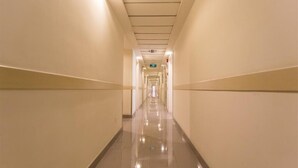 A long, narrow hallway with a shiny tiled floor and cream-colored walls.