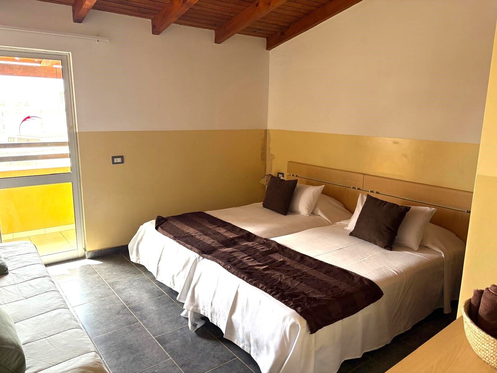 Un letto matrimoniale con testiera in legno, una coperta marrone e due cuscini.