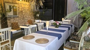 A dining area with white tables and chairs, decorated with candles and woven placemats. - Porta Do Vento (Sal)