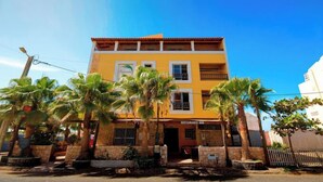 A two-story building with a yellow facade, multiple windows, and a sign that reads "RESTAURANTE." - Porta Do Vento (Sal)
