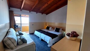 A hotel room with a bed, a sofa, a window with curtains, a ceiling fan, and a nightstand with a lamp. - Porta Do Vento (Sal)
