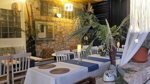 An outdoor dining area with stone walls, white furniture, and potted plants. - Porta Do Vento (Sal)