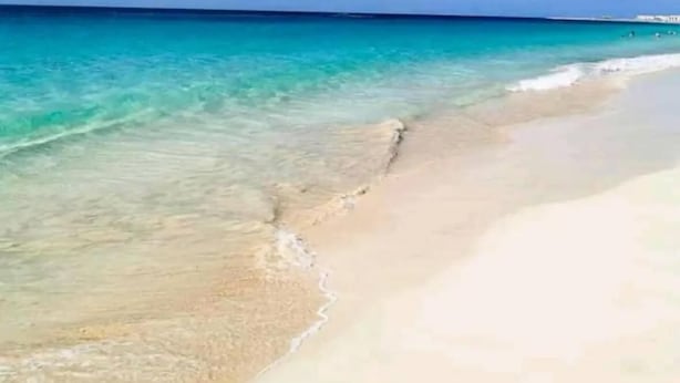 A beach with clear turquoise water and a sandy shore under a partly cloudy sky. - Porta Do Vento (Sal)