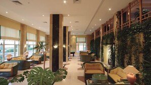 Spaziosa hall con comodi posti a sedere, tavolo da biliardo e parete decorata con piante.