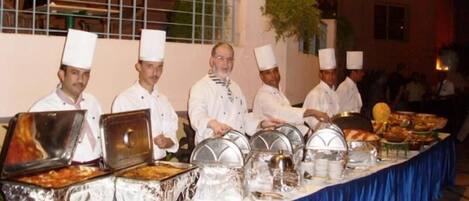 A buffet setup with multiple food stations and chefs in uniform.