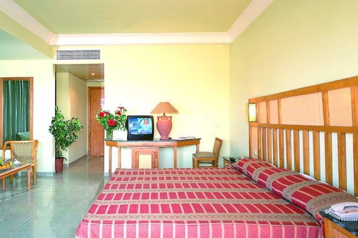 A hotel room with a large bed, a desk with a computer, a chair, and a television.