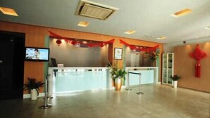 A hotel reception area with a reception desk, a television mounted on the wall, and a red decorative element on the wall. - Jinjiang Inn Nanjing Train Station (Nanjing)